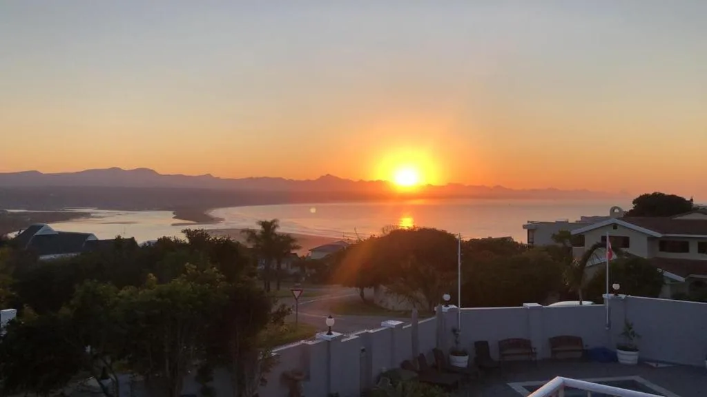 Golden sunset over Plettenberg Bay lagoon with mountains silhouetted