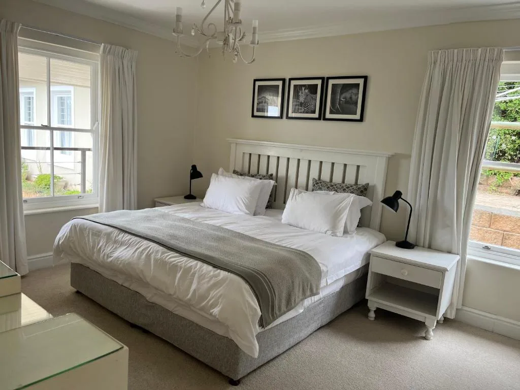 Bright bedroom with double bed, white bedding, windows overlooking garden