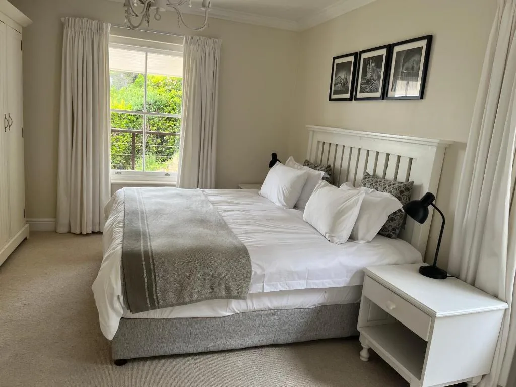 Bright bedroom with white bed frame, garden views through large windows
