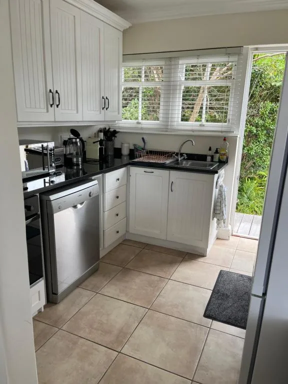 Modern kitchen with white cabinetry, black countertops, stainless steel appliances