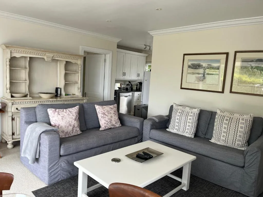 Spacious lounge with grey sofas, white coffee table, and framed artwork