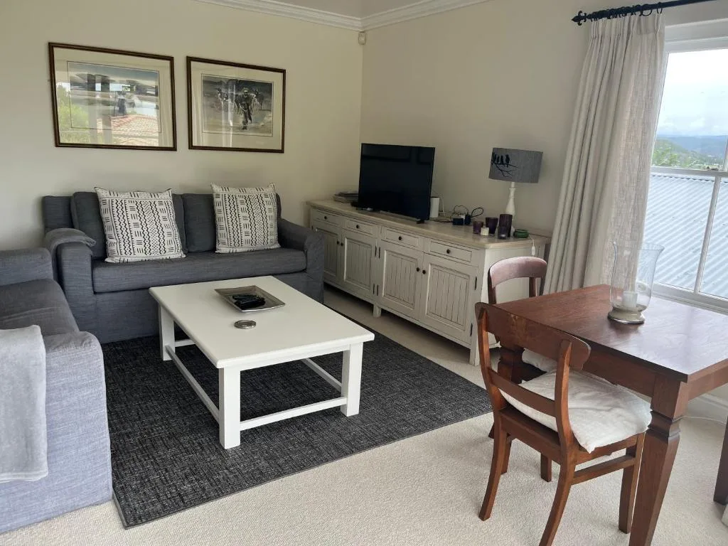 Spacious lounge with gray sofa, white coffee table, and ocean views through sliding doors