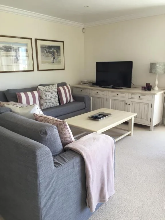 Comfortable lounge with grey sofas, TV, and framed artwork on walls