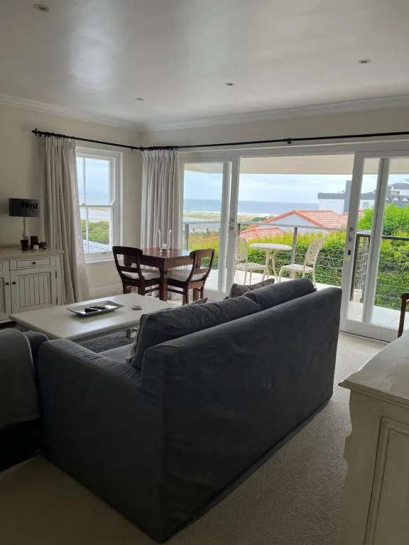 Spacious lounge with dark sofa, ocean views through large glass doors