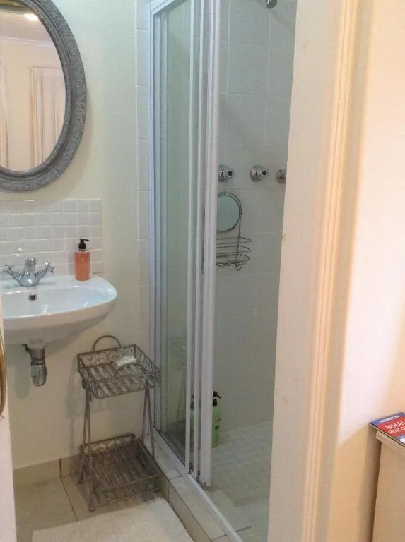 Modern bathroom with pedestal sink, shower enclosure, and circular mirror