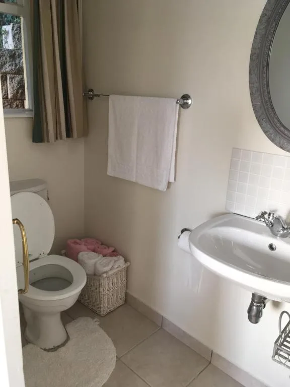 Clean bathroom with toilet, round sink, towel rack, and circular mirror