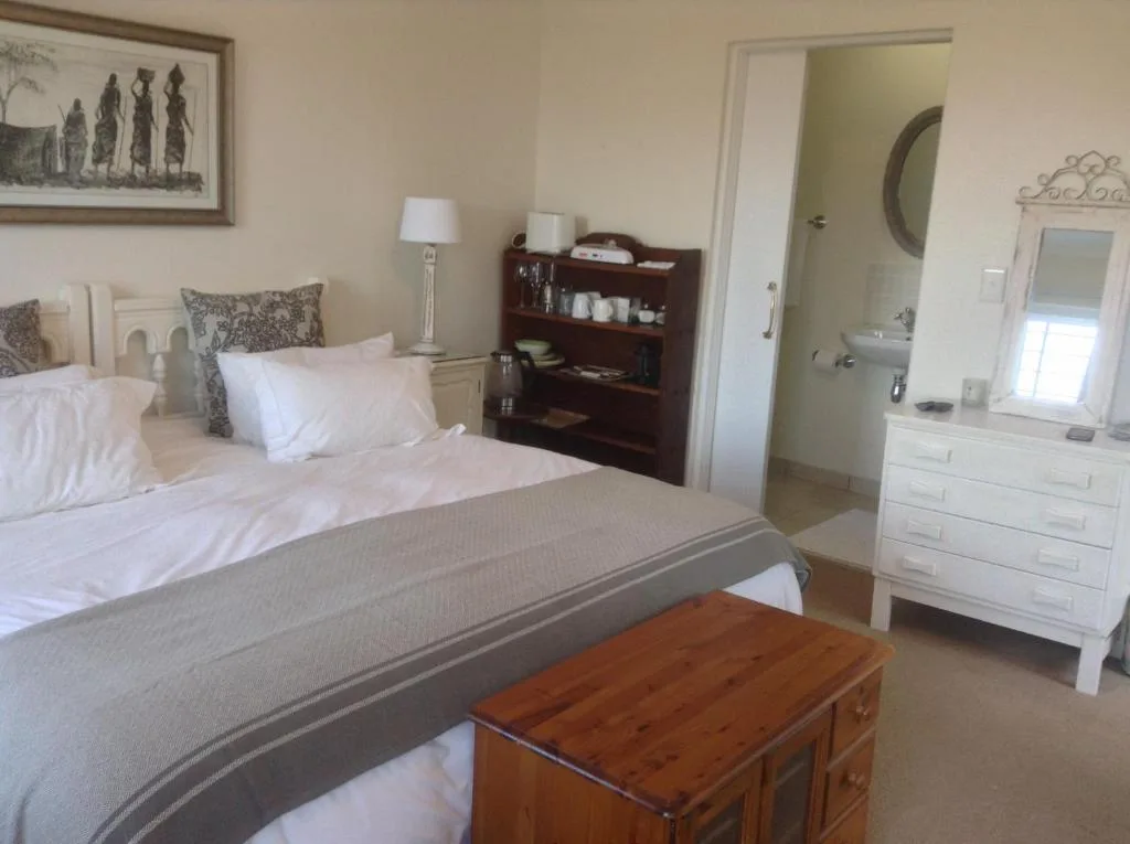 Spacious bedroom with queen bed, white dresser, and ensuite bathroom visible
