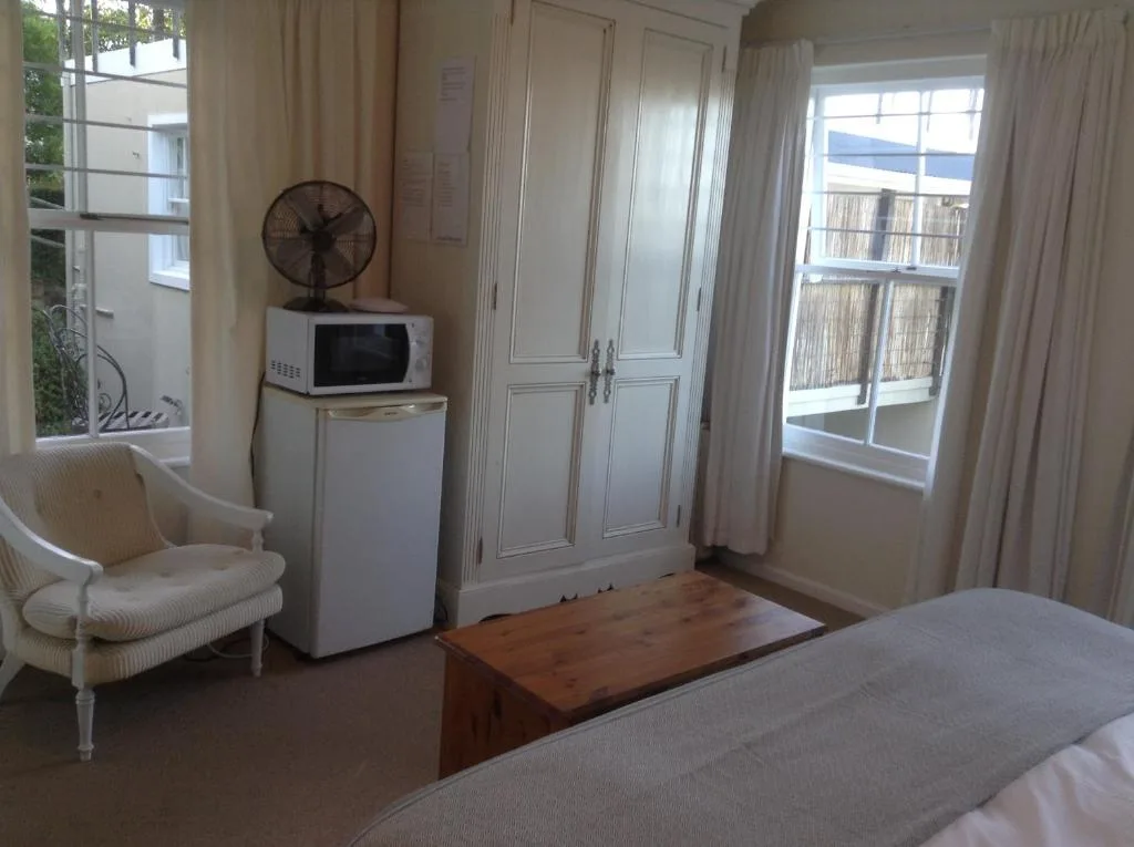 Spacious bedroom with bed, armchair, wardrobe, and ocean view through glass doors