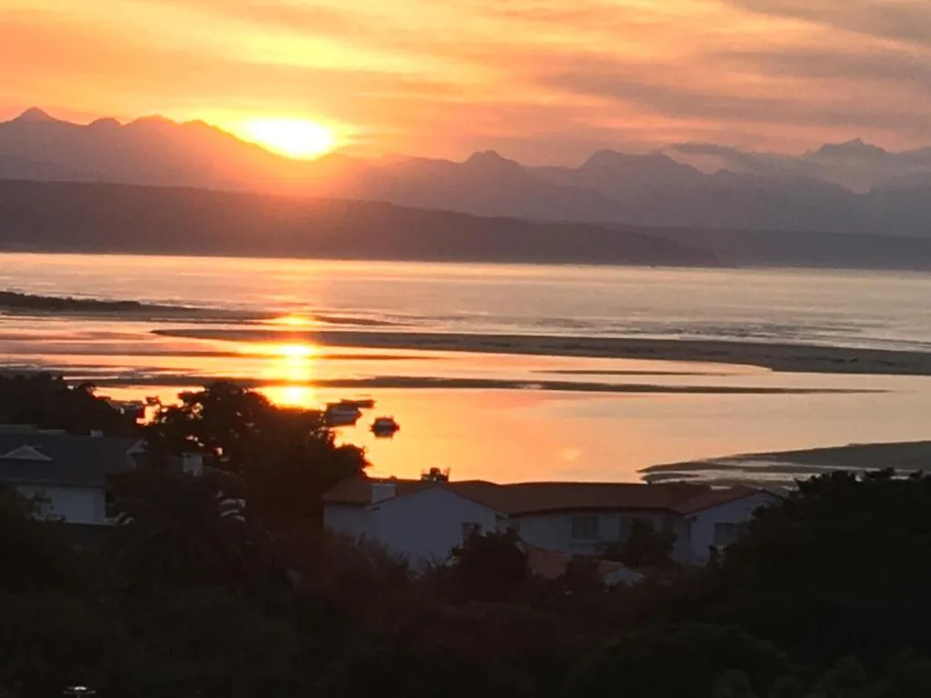 Golden sunset over lagoon with mountains and coastal properties silhouetted