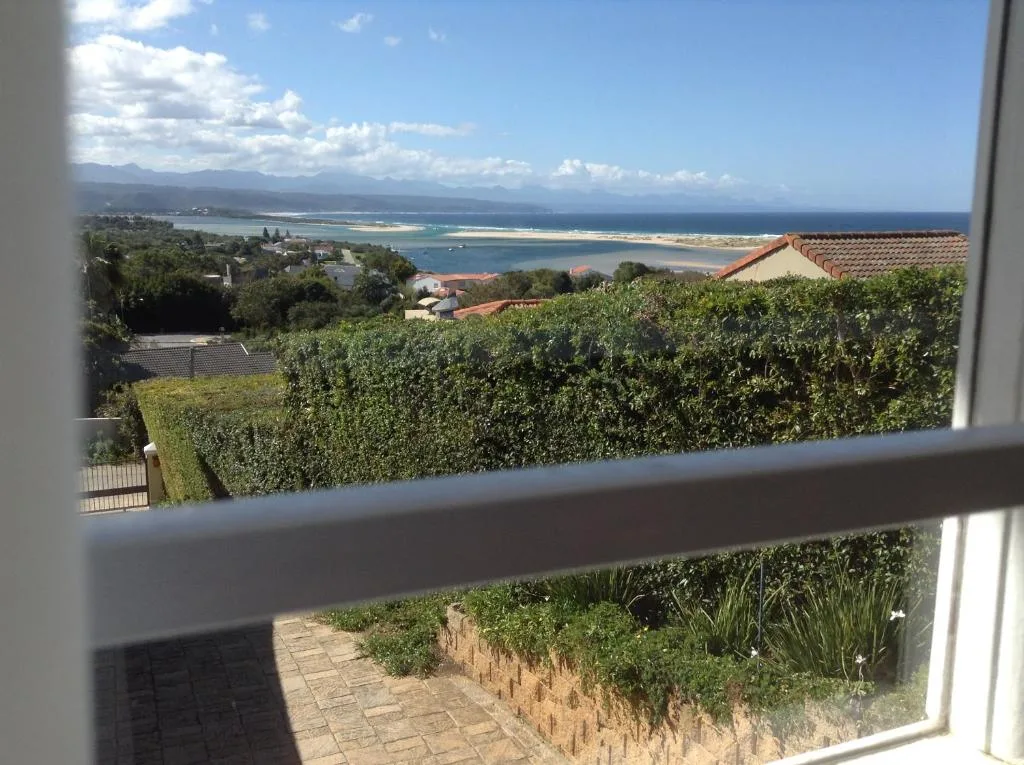 Expansive coastal vista showing bay, beach, and distant mountains from window