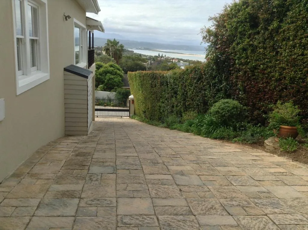 Lagoon and coastline vista from paved garden pathway with lush hedges