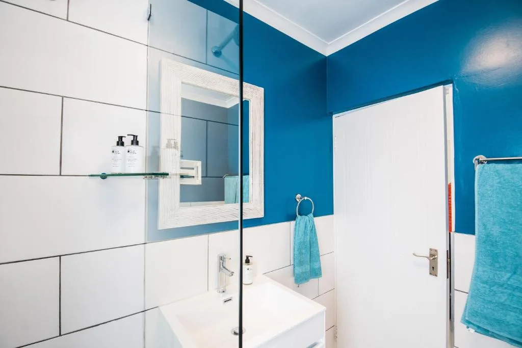 Modern bathroom with blue accent wall, white vanity, and glass shower enclosure