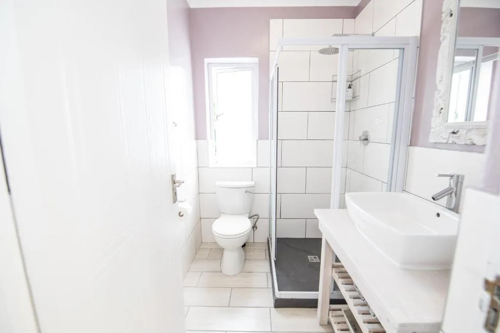 Modern bathroom with white subway tiles, double vanity sink, and walk-in shower