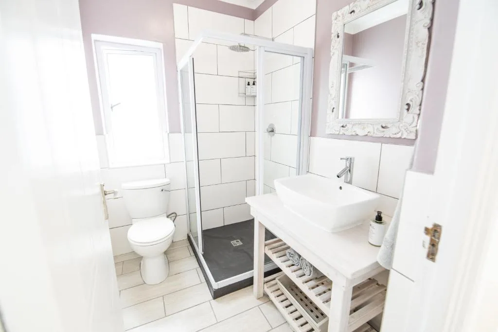 Modern bathroom with walk-in shower, white vanity, and decorative mirror