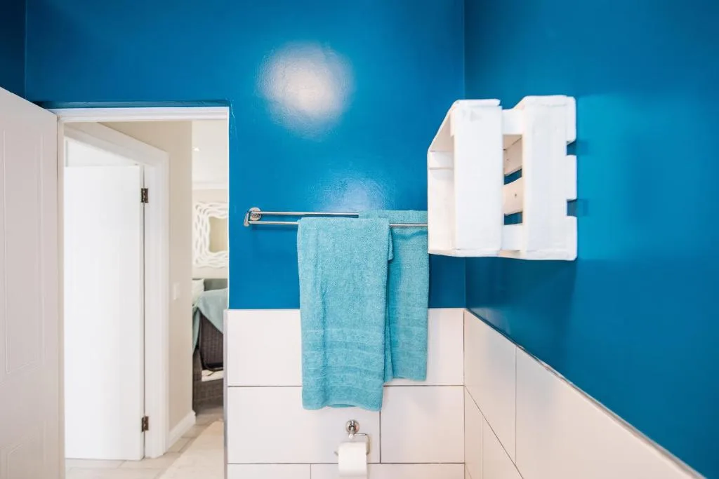 Modern bathroom with vibrant blue walls and white towel rack