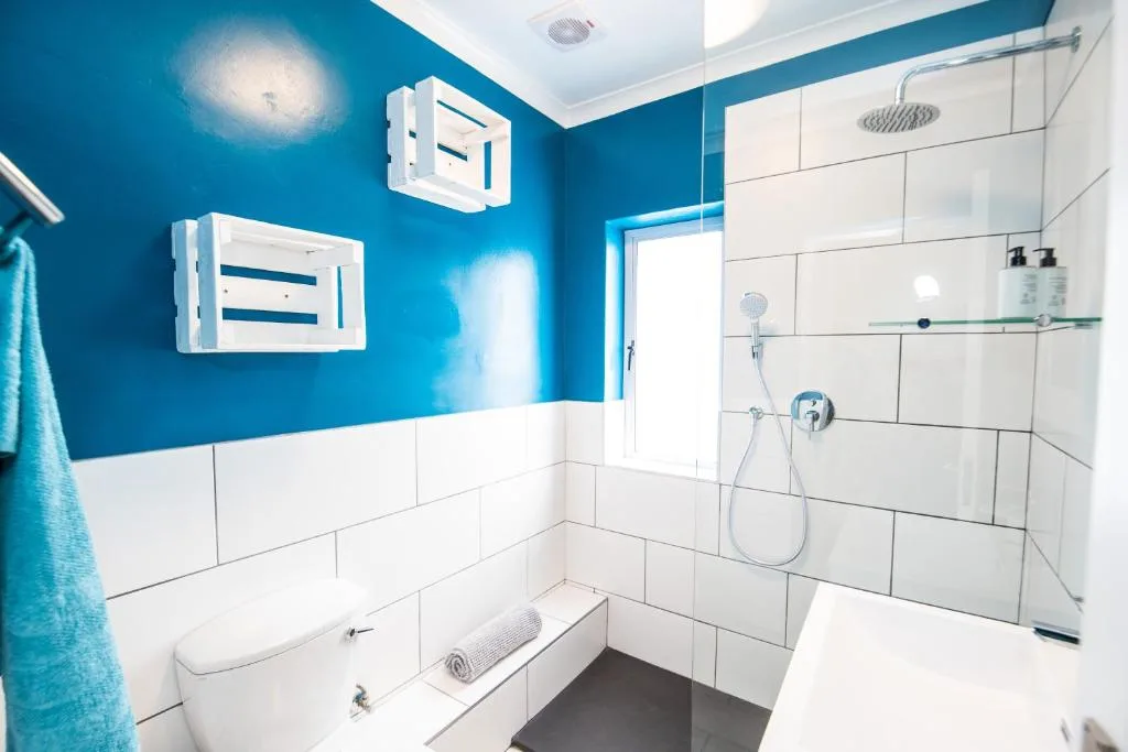 Modern bathroom with bright blue walls, white subway tiles, and rainfall shower