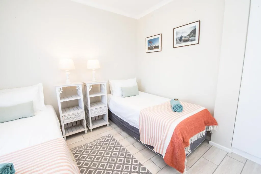 Bright bedroom with two single beds and white storage shelving units