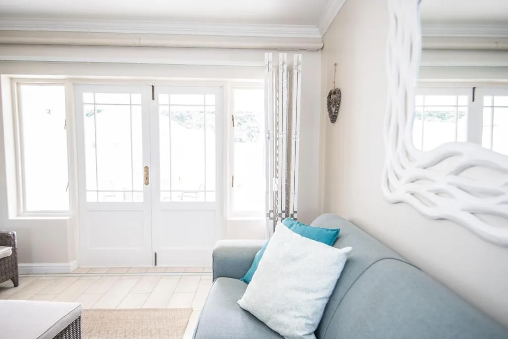 Bright bedroom with bed, lounge seating, and glass doors overlooking garden