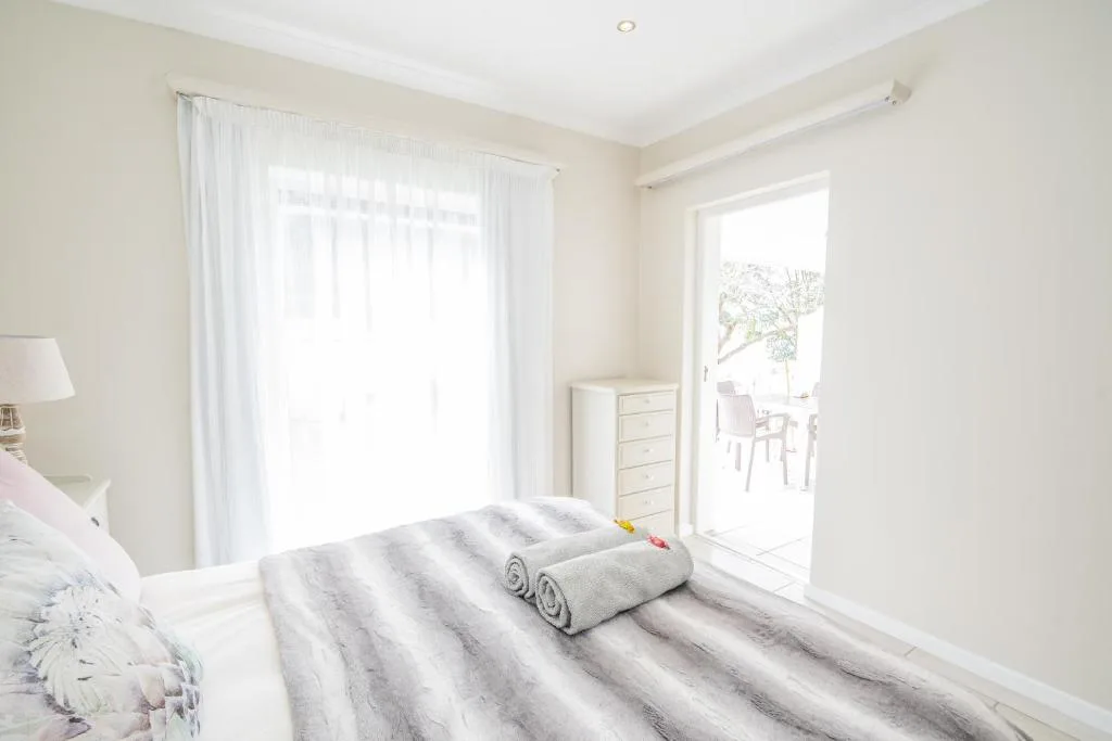 Bright bedroom with striped bedding, rolled towels, and ocean view doors