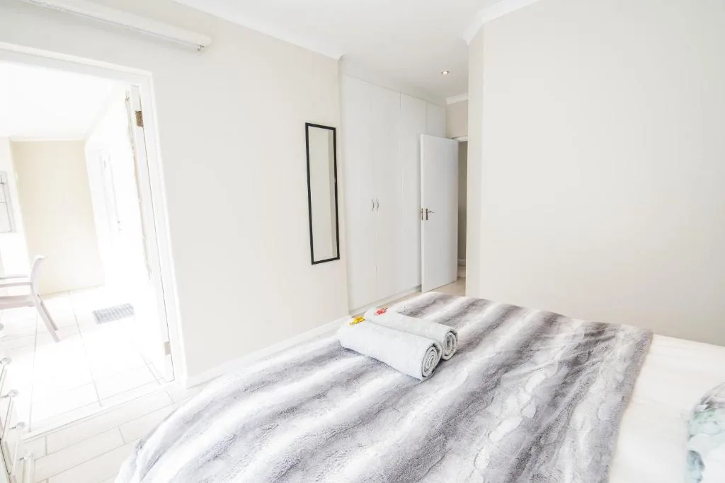 Bright bedroom with striped bedding, wardrobe, and ensuite bathroom access