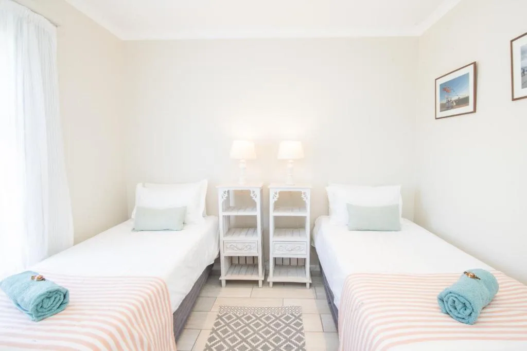 Bright twin bedroom with two single beds and white bedside tables between them