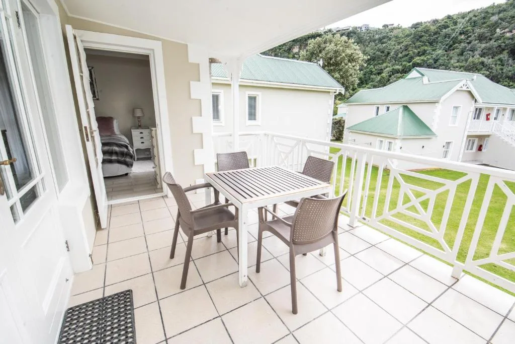 Outdoor patio with dining table, chairs, and mountain views beyond railing