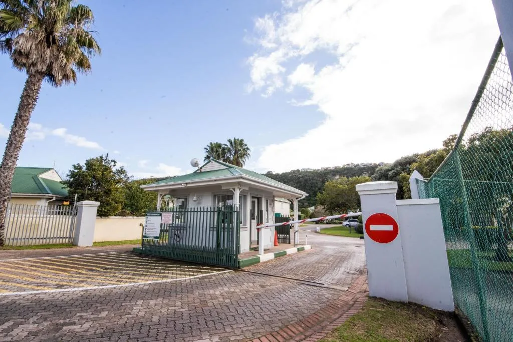 Green-roofed cottage entrance with brick driveway and lush garden surroundings