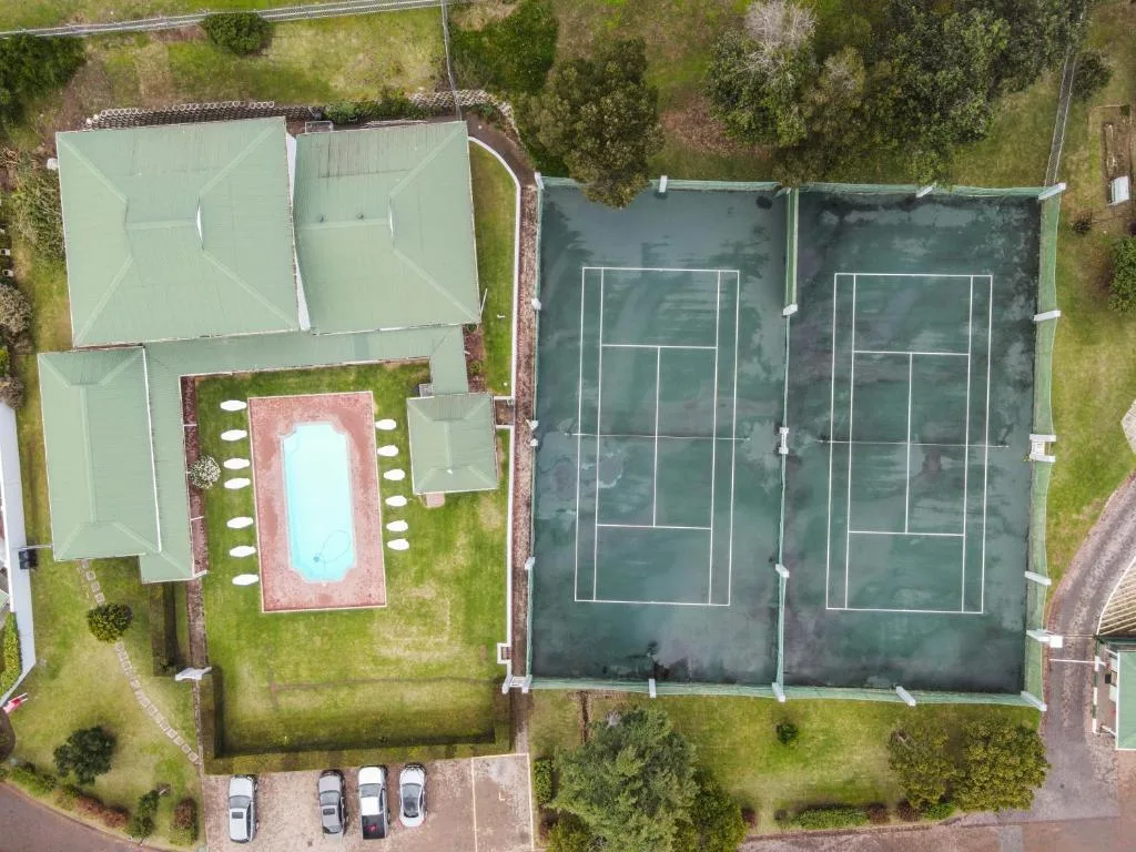 Aerial view of property with pool, tennis courts, and manicured gardens