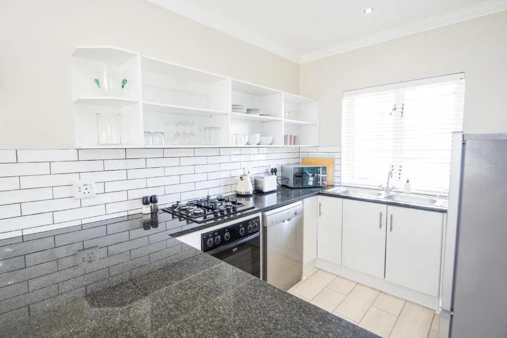 Modern white kitchen with gas cooktop, subway tile backsplash, and open shelving