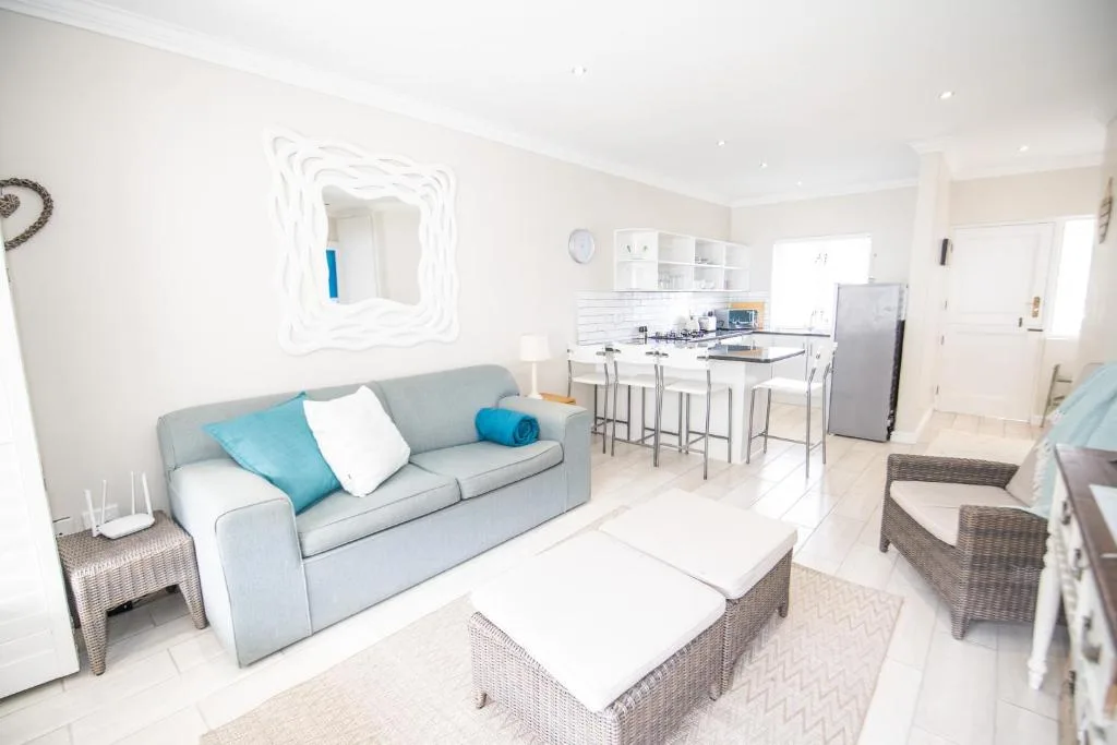 Modern open-plan lounge with gray sofa, blue accents, and kitchen beyond