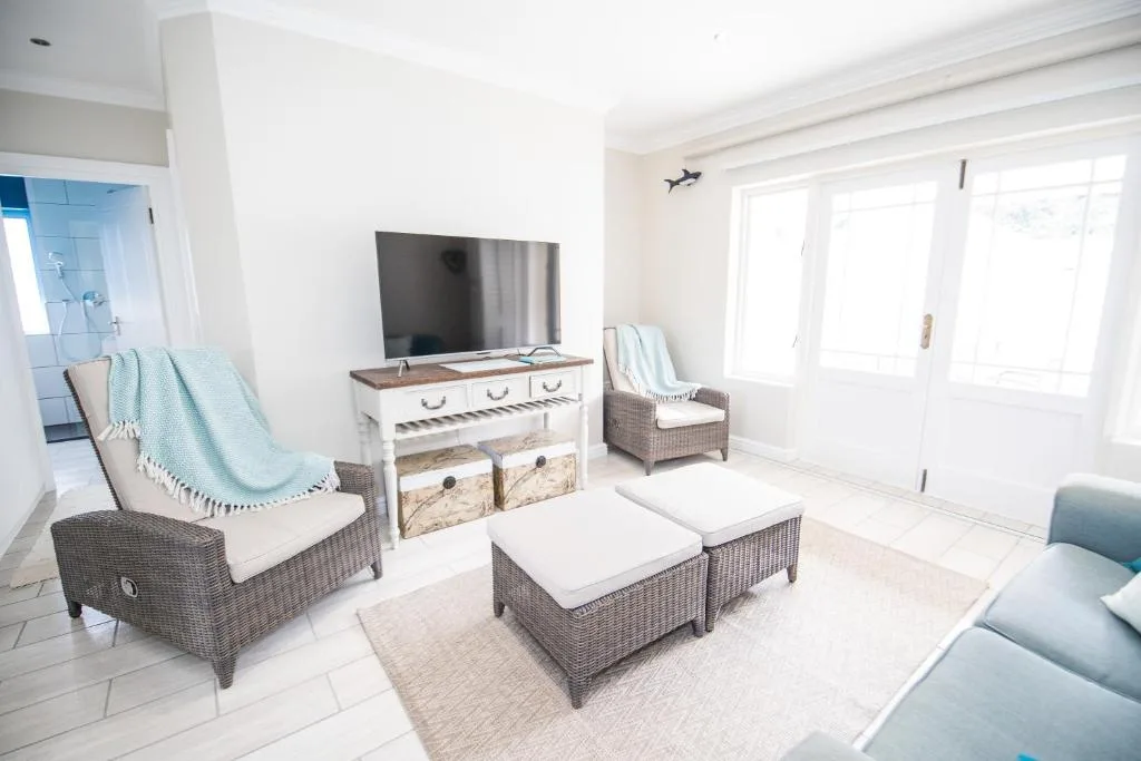 Bright lounge with wicker seating, TV unit, and coastal decor accents