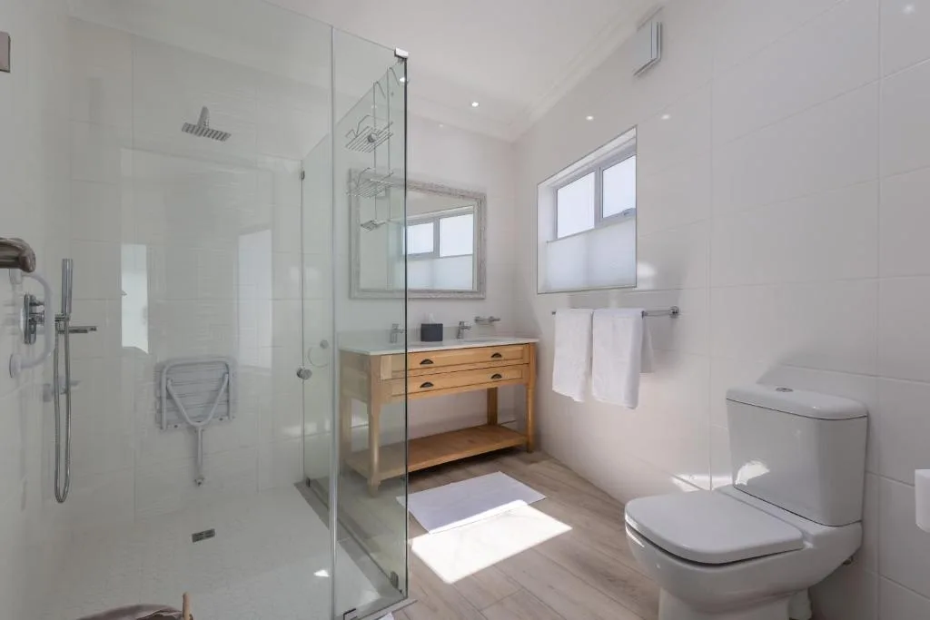 Modern bathroom with walk-in shower, wooden vanity, and toilet