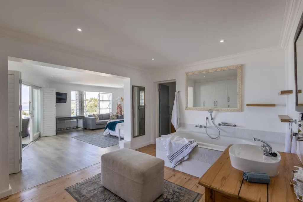 Spacious ensuite bedroom with modern bathroom, soaking tub, and ocean views