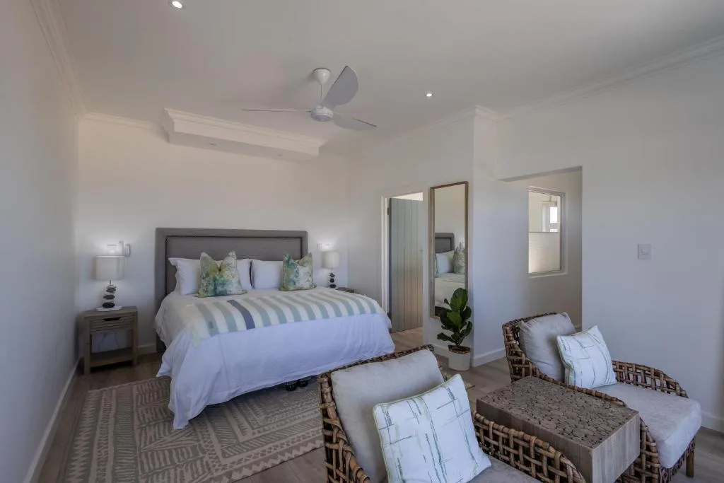 Spacious bedroom with queen bed, wicker seating, and ceiling fan