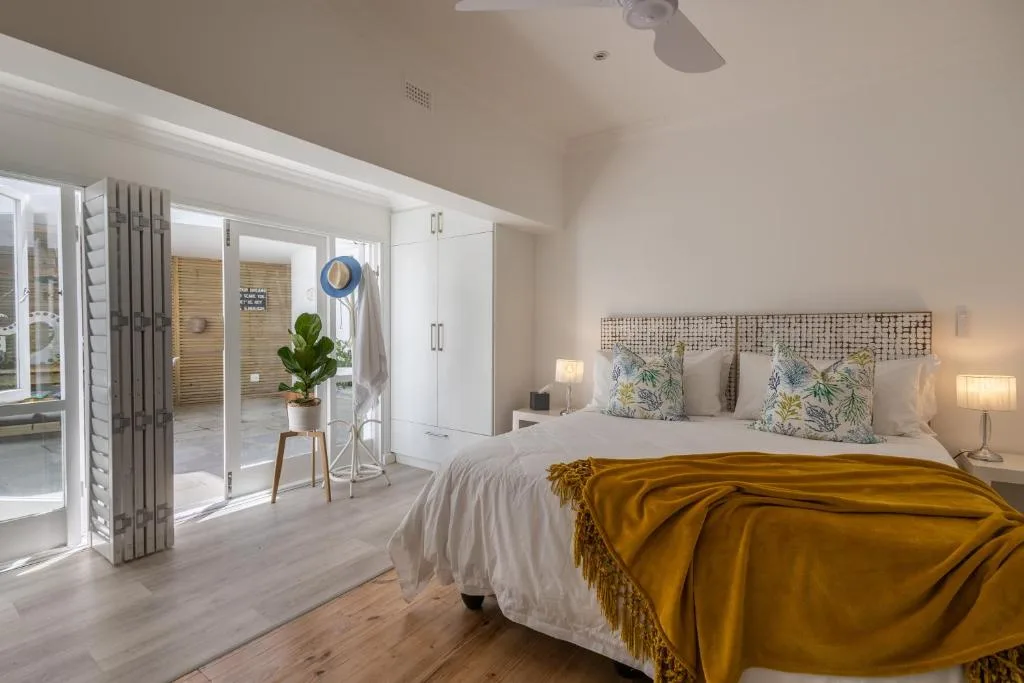 Bright bedroom with queen bed, botanical pillows, and deck access doors