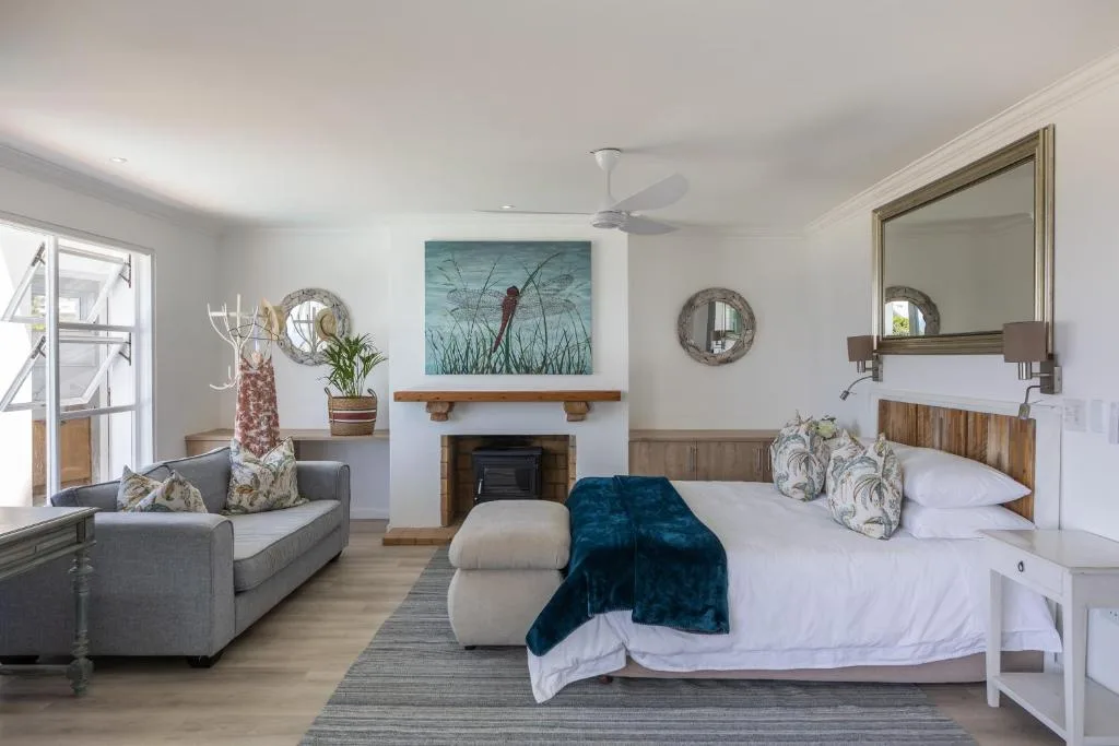 Spacious bedroom with fireplace, lounge seating area, and coastal decor