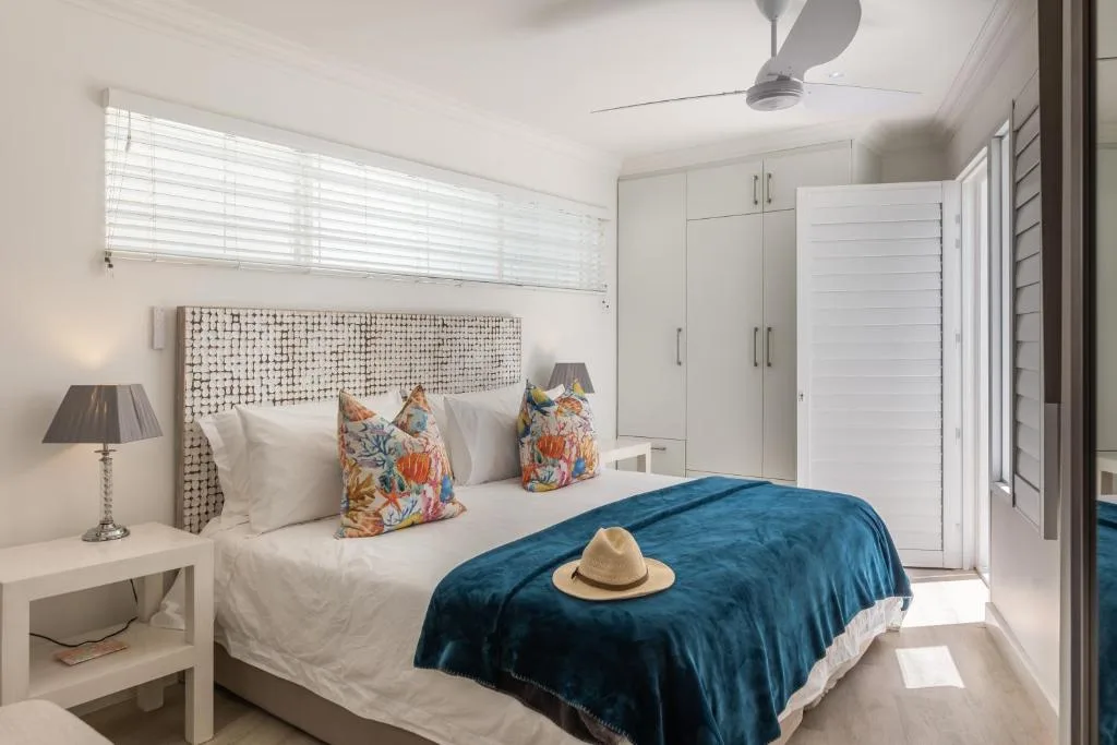 Bright bedroom with textured headboard, colorful pillows, and blue bedcover