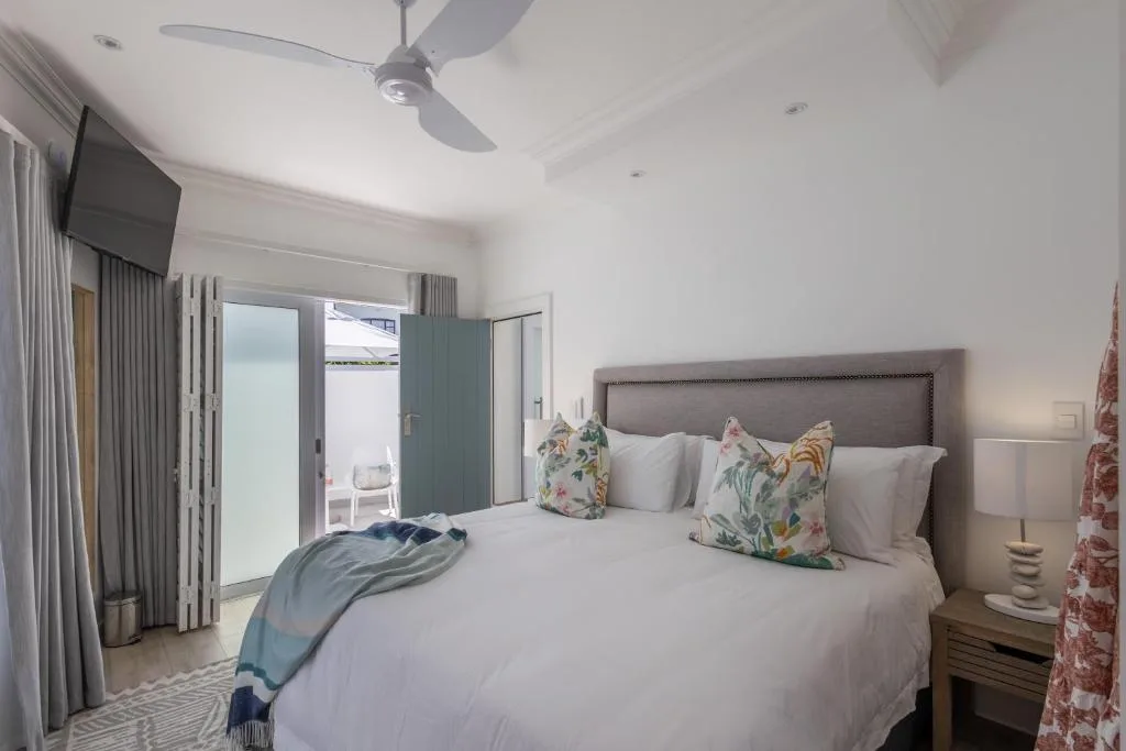 Spacious bedroom with king bed, patterned cushions, and deck access doors
