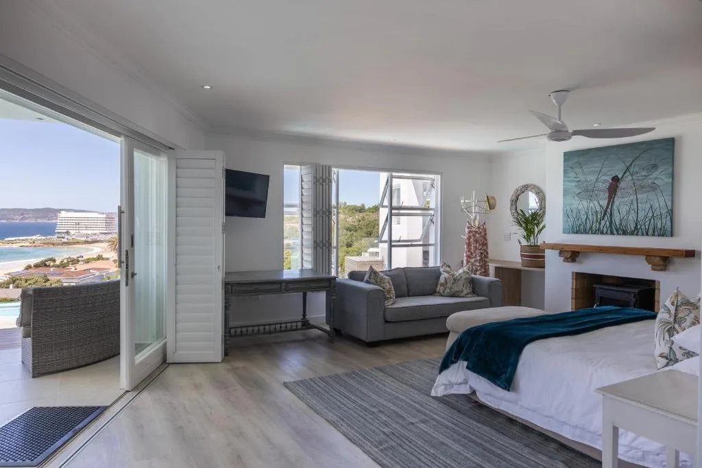 Spacious bedroom with ocean view, bed, lounge seating, and coastal landscape vista