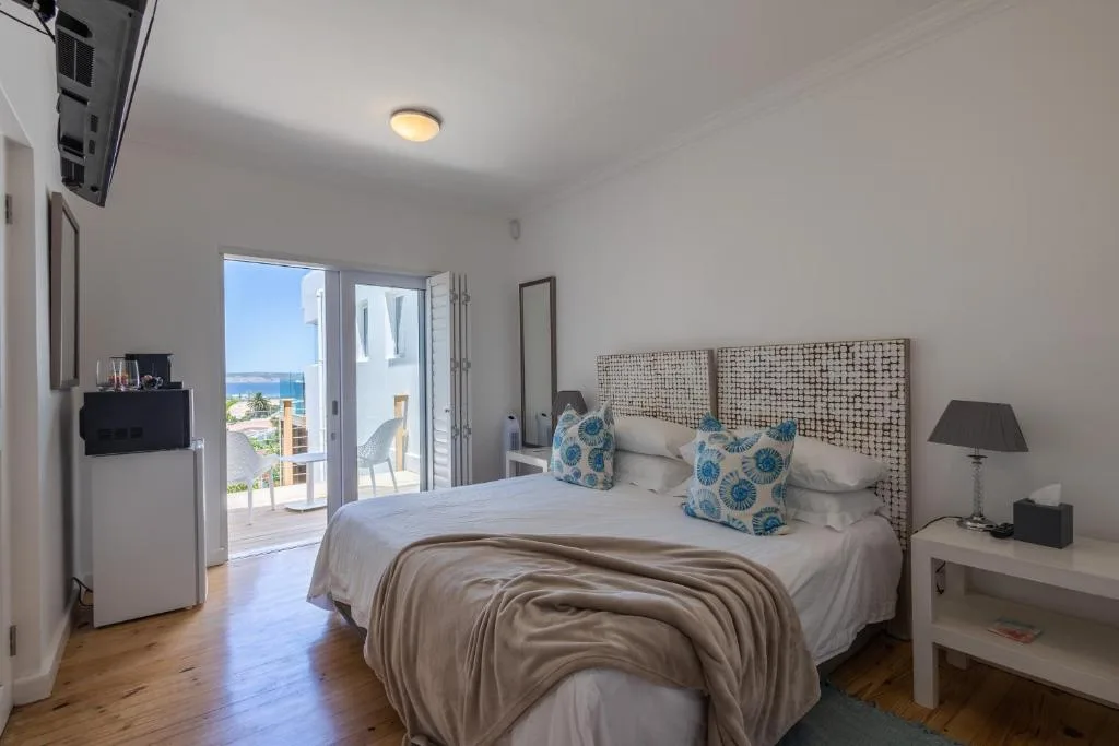 Bright bedroom with ocean view through glass doors and sea views beyond