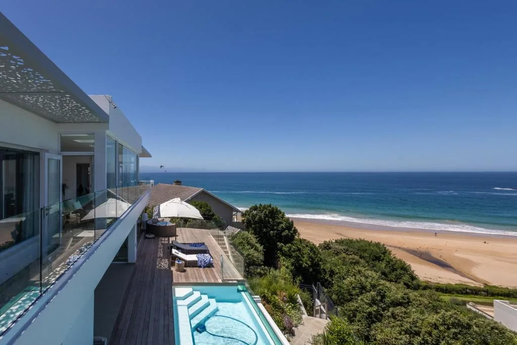 Modern oceanfront deck with pool overlooking pristine beach and turquoise waters