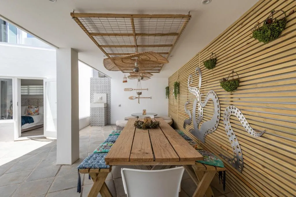 Covered outdoor dining area with wooden table and decorative coastal wall art