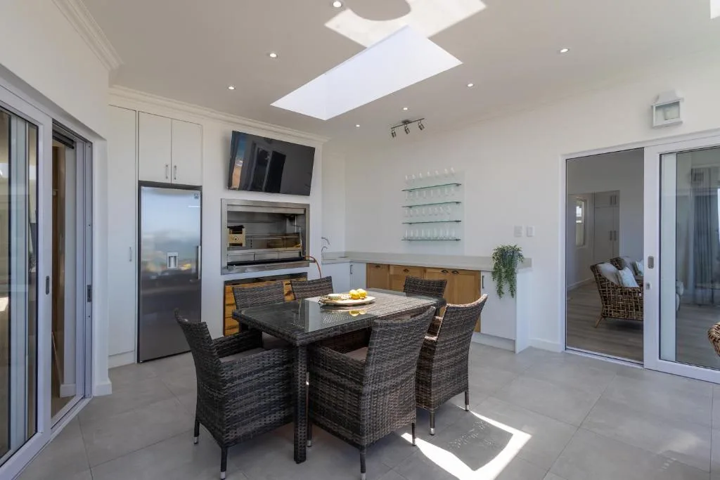 Modern dining area with woven chairs and table, open kitchen beyond