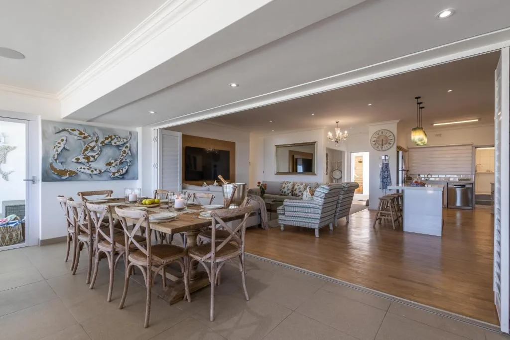 Open-plan dining area with wooden table and cross-back chairs overlooking lounge