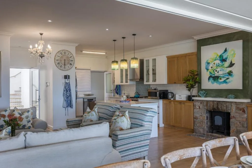 Open-plan living area with striped armchair, fireplace, and kitchen beyond