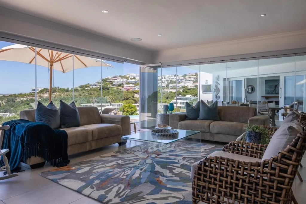 Modern lounge with sofas, ocean and hillside views through floor-to-ceiling windows