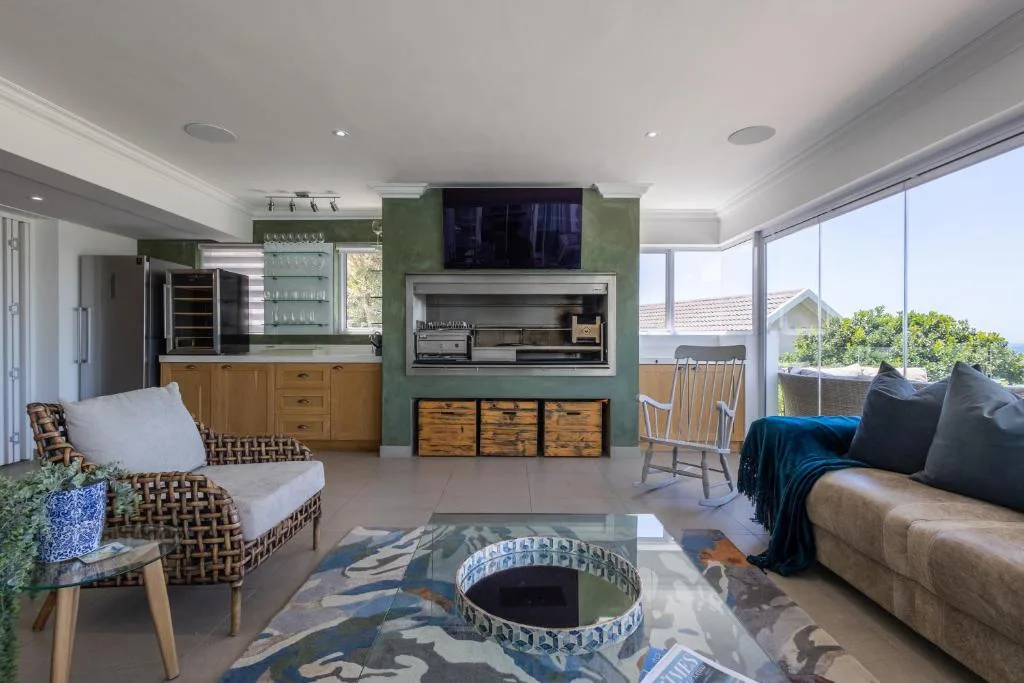 Modern lounge with sofa, armchair, fireplace, and ocean views through large windows