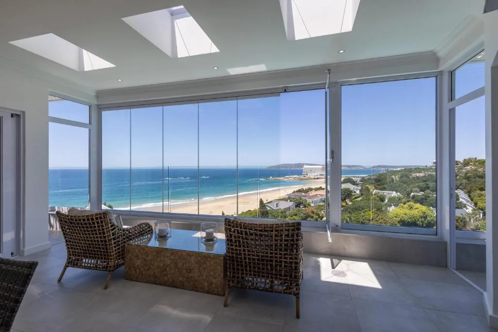 Panoramic ocean and beach view through floor-to-ceiling windows from lounge area