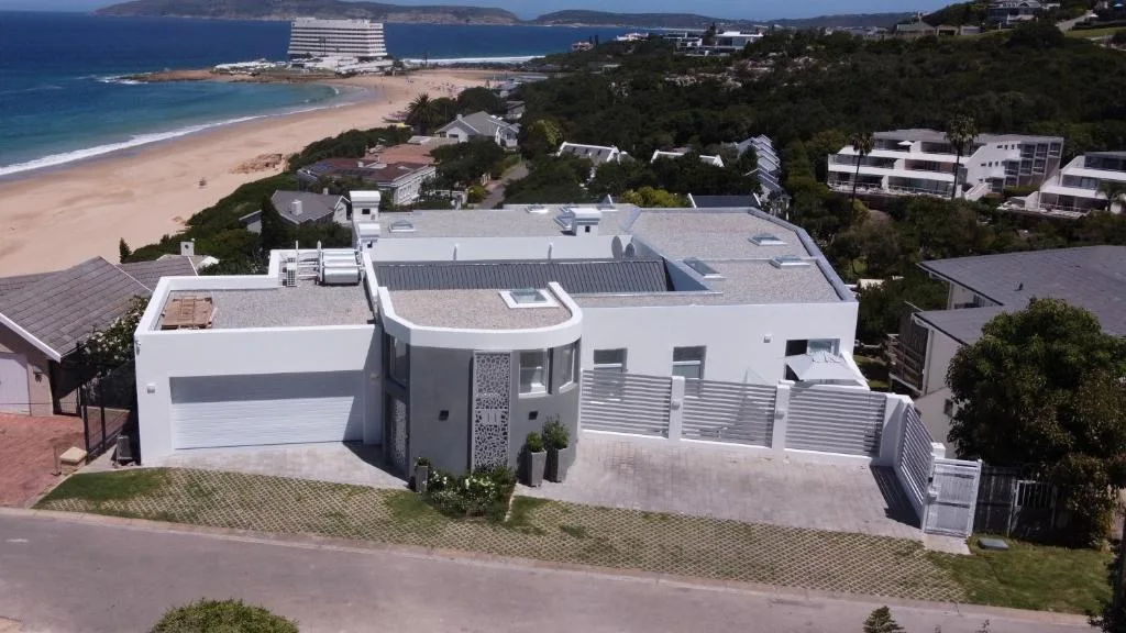 Aerial view of modern beachfront villa with ocean and coastal town landscape
