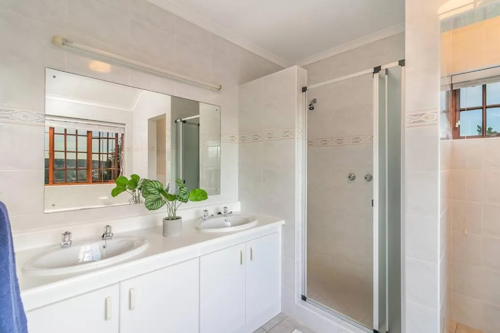 Bright white bathroom with dual vanity sinks and walk-in shower enclosure